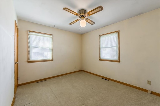 spare room with light carpet, plenty of natural light, visible vents, and baseboards