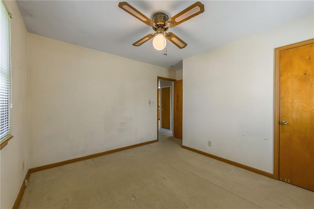 unfurnished room with baseboards, light carpet, and a ceiling fan