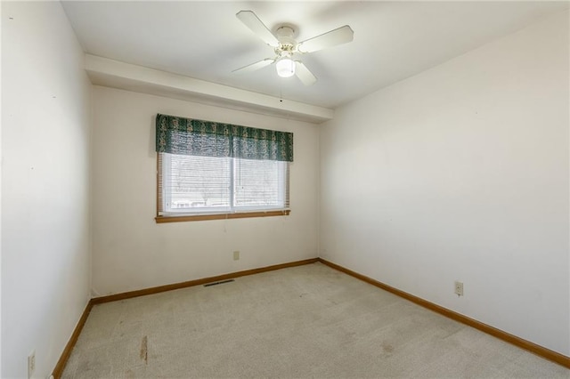 spare room with visible vents, light colored carpet, baseboards, and ceiling fan