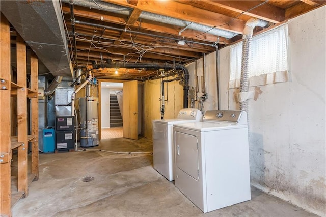 basement featuring stairway, heating unit, water heater, and washer and clothes dryer