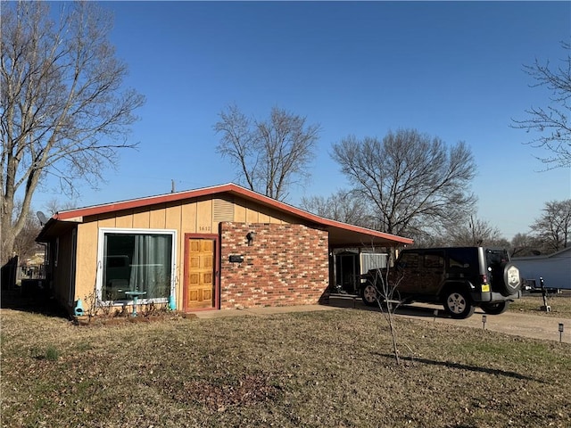 view of front of home featuring an attached carport, concrete driveway, brick siding, and a front yard