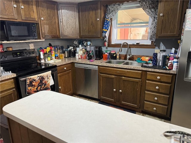 kitchen featuring black appliances, light countertops, and a sink