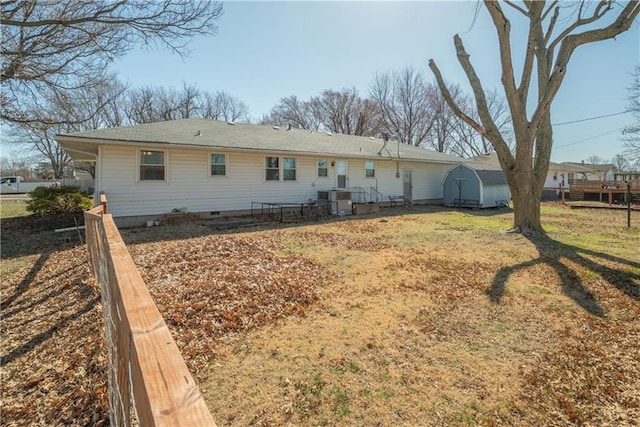 back of property with an outbuilding, a storage unit, central AC, and crawl space