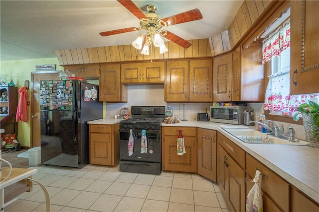 kitchen with brown cabinetry, a sink, black appliances, light countertops, and backsplash