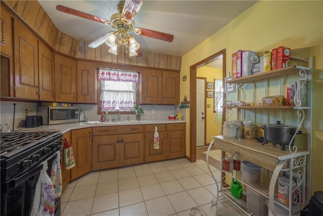 kitchen with stainless steel microwave, brown cabinetry, light tile patterned flooring, and light countertops