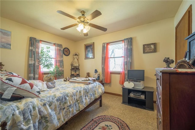 carpeted bedroom featuring multiple windows, baseboards, and ceiling fan