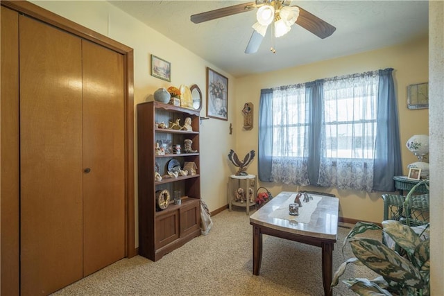 living room with baseboards, light colored carpet, and a ceiling fan