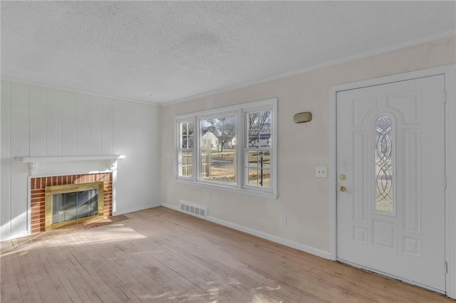 unfurnished living room featuring visible vents, baseboards, a fireplace, wood finished floors, and a textured ceiling