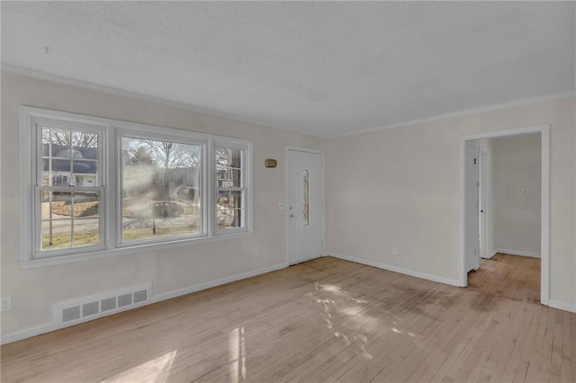 unfurnished living room with a wealth of natural light, visible vents, a textured ceiling, and wood-type flooring