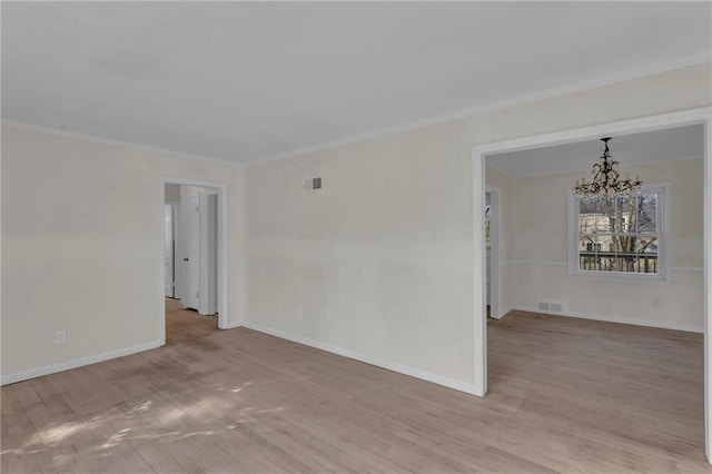 empty room with an inviting chandelier, wood finished floors, visible vents, and ornamental molding