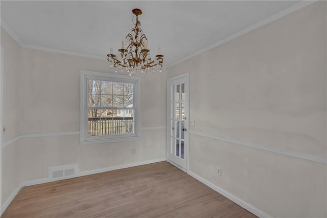 unfurnished dining area with visible vents, a notable chandelier, ornamental molding, wood finished floors, and baseboards