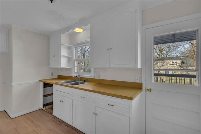 kitchen with a sink, light wood-type flooring, open shelves, and white cabinetry