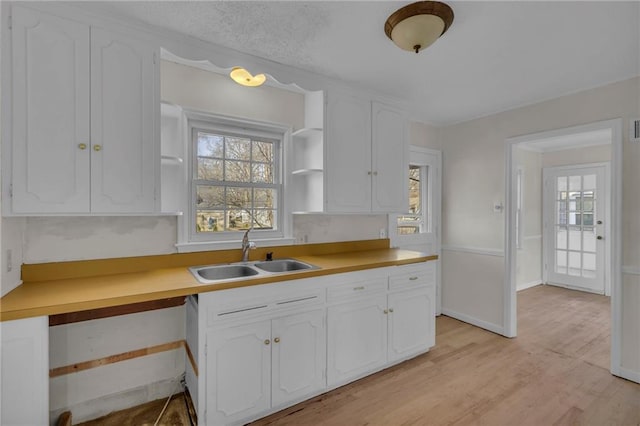 kitchen with a sink, open shelves, light wood-style flooring, and white cabinetry