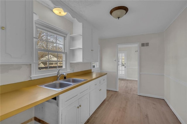 kitchen with visible vents, open shelves, a sink, white cabinets, and light wood-type flooring