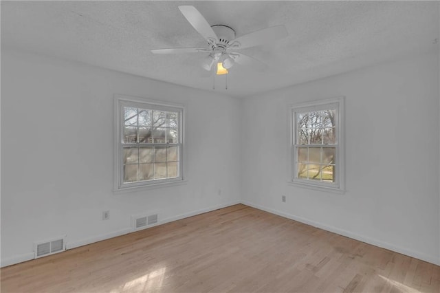 spare room with wood finished floors, visible vents, and a textured ceiling