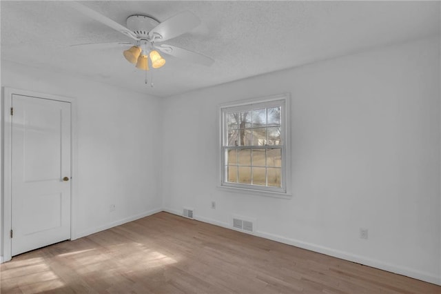 unfurnished room with visible vents, baseboards, a textured ceiling, and wood finished floors