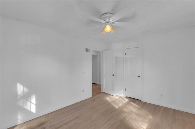 interior space with visible vents, a ceiling fan, baseboards, and wood finished floors