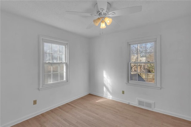 empty room with visible vents, baseboards, light wood-type flooring, and ceiling fan