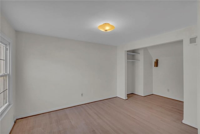 empty room featuring visible vents, baseboards, and wood finished floors