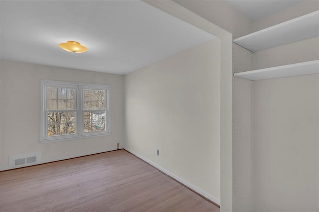 empty room with visible vents, baseboards, and wood finished floors