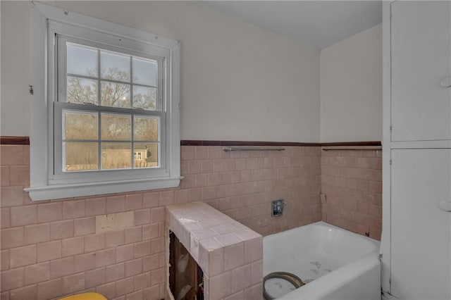 full bath with a wainscoted wall, a garden tub, and tile walls