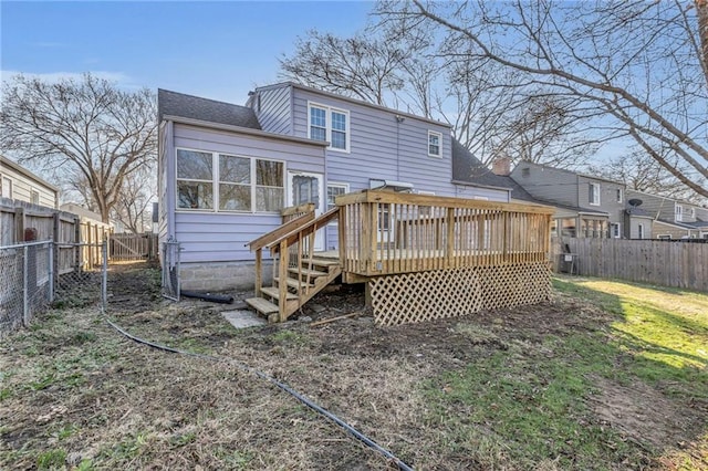 back of property featuring a yard, a wooden deck, a fenced backyard, and a sunroom