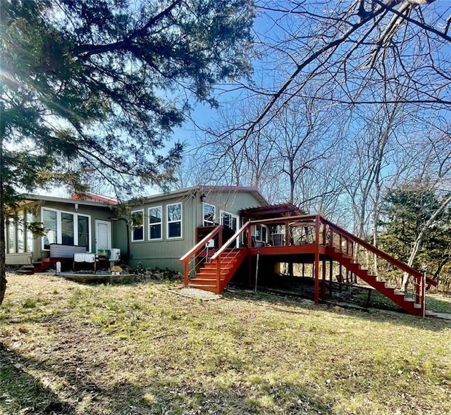 rear view of property featuring a deck, stairway, and a yard