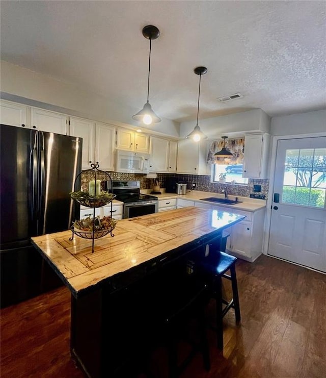 kitchen featuring stainless steel electric range oven, dark wood-style floors, white microwave, freestanding refrigerator, and a sink