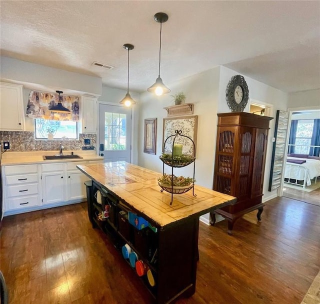 kitchen featuring dark wood-type flooring, a sink, tasteful backsplash, white cabinets, and light countertops