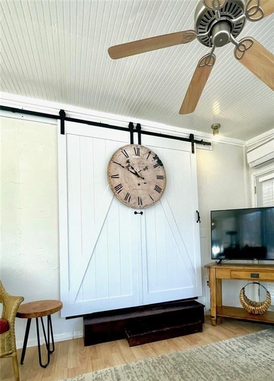 room details featuring ceiling fan, a barn door, wood finished floors, and a wall unit AC