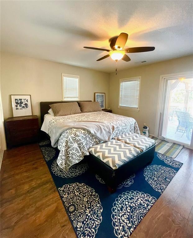 bedroom featuring access to exterior, multiple windows, and wood finished floors