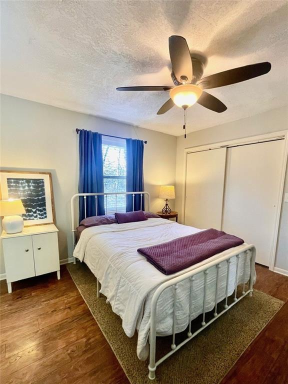 bedroom with baseboards, ceiling fan, wood finished floors, a closet, and a textured ceiling