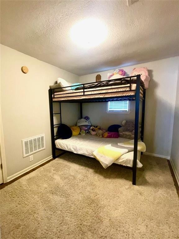 carpeted bedroom with visible vents, a textured ceiling, and baseboards