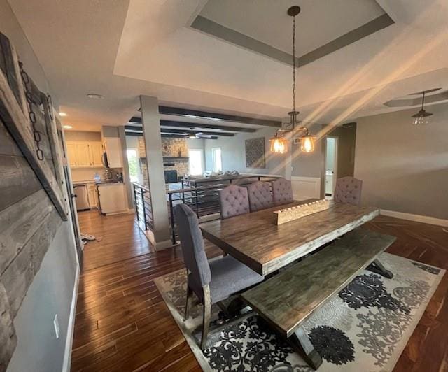 dining room with dark wood finished floors, a raised ceiling, and baseboards