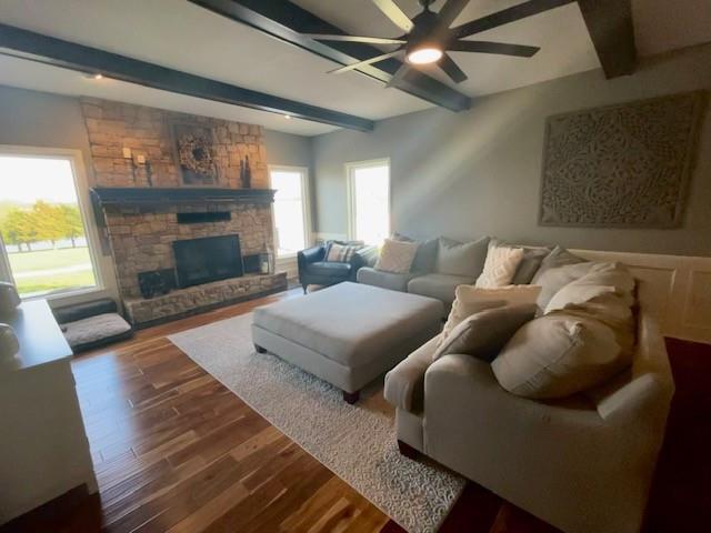 living area with a wealth of natural light, beamed ceiling, ceiling fan, and wood finished floors