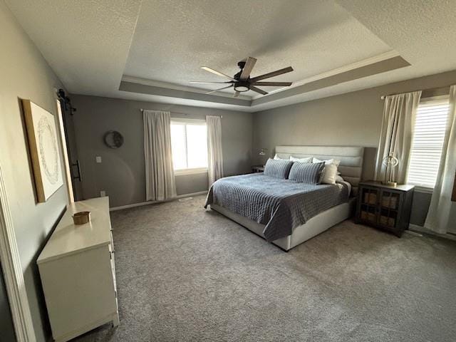 carpeted bedroom featuring a tray ceiling, a ceiling fan, and a textured ceiling