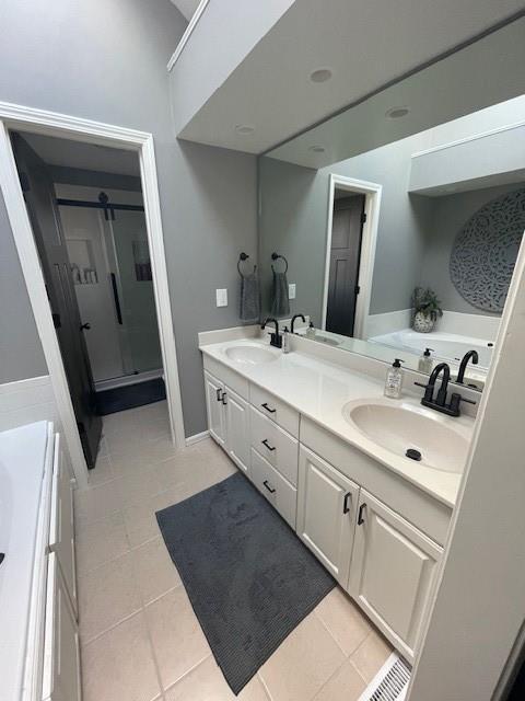 full bath featuring double vanity, tile patterned flooring, a shower stall, and a sink