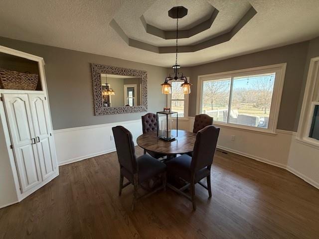 dining area with a notable chandelier, a tray ceiling, a textured ceiling, dark wood-style floors, and baseboards