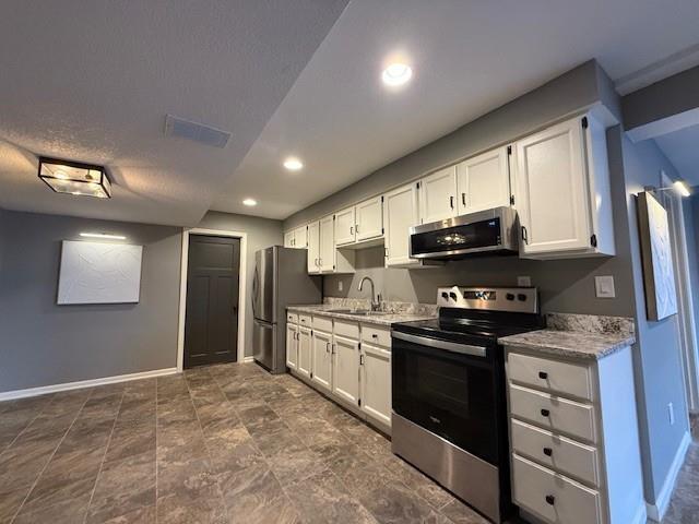 kitchen with visible vents, white cabinetry, stainless steel appliances, and a sink