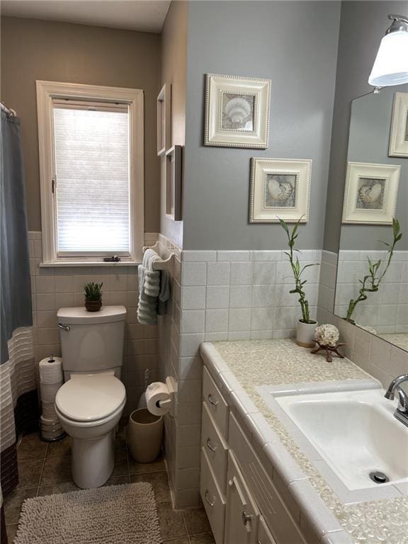 full bathroom featuring vanity, tile patterned floors, toilet, and a wainscoted wall