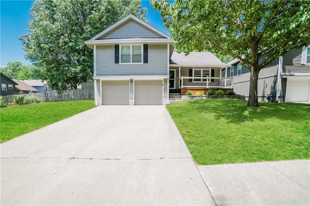 tri-level home with driveway, covered porch, a front lawn, and fence