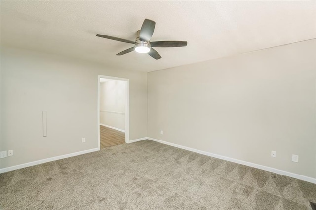 empty room with ceiling fan, a textured ceiling, baseboards, and carpet