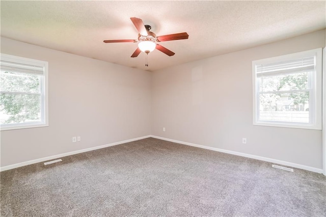 carpeted spare room with visible vents, baseboards, a textured ceiling, and ceiling fan