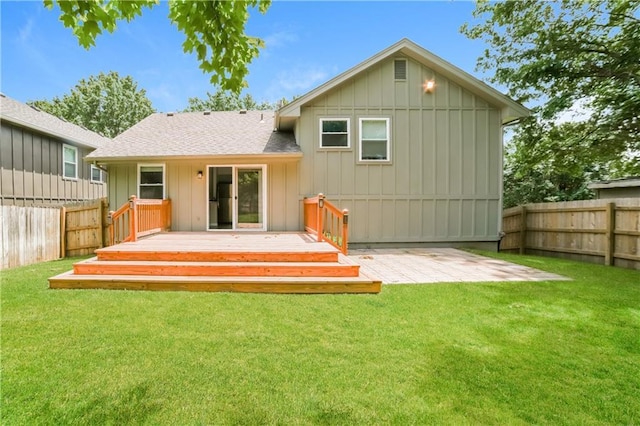 rear view of property with a deck, a lawn, board and batten siding, and a fenced backyard