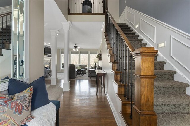 16520 NW 178th St, Platte City, MO 64079 - staircase with wood finished floors, a fireplace, a ceiling fan, and decorative columns