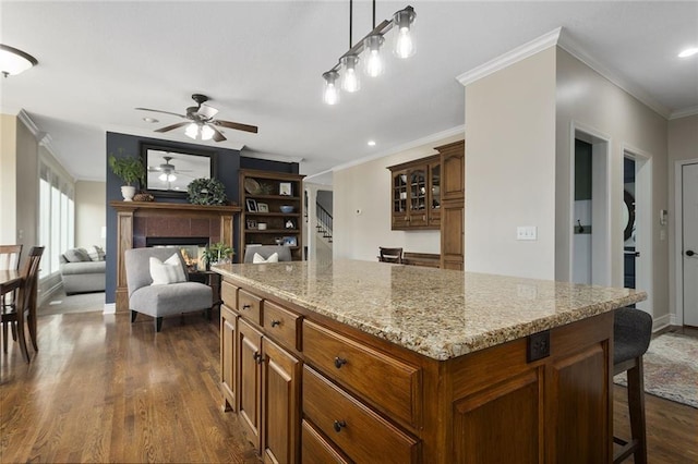 16520 NW 178th St, Platte City, MO 64079 - kitchen with dark wood-style floors, a tile fireplace, a breakfast bar area, ceiling fan, and ornamental molding