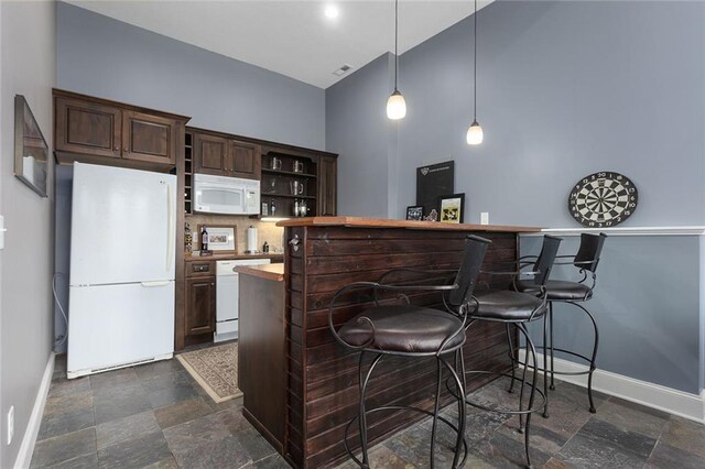 16520 NW 178th St, Platte City, MO 64079 - kitchen with white appliances, dark stone finish floors, a kitchen bar, dark brown cabinets, and a high ceiling