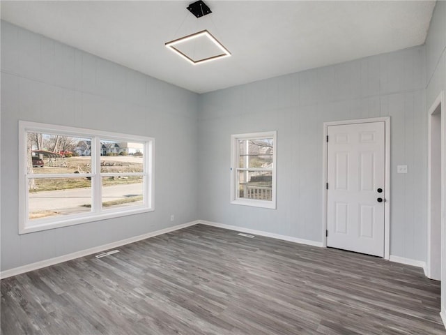 spare room with visible vents, baseboards, and wood finished floors