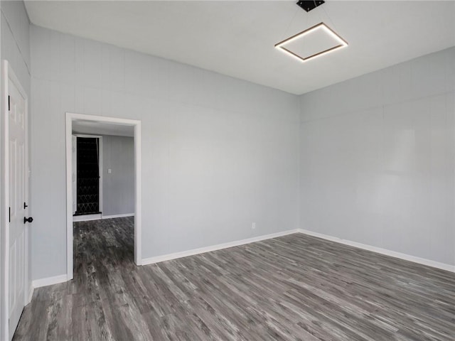 spare room with baseboards and wood finished floors