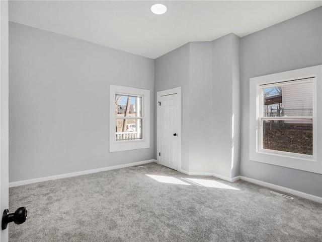 unfurnished room featuring carpet flooring, visible vents, and baseboards